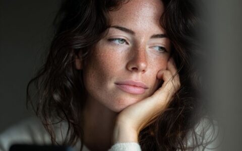 Woman thoughtfully using a smartphone, representing human-centered AI, digital consent, and online safety